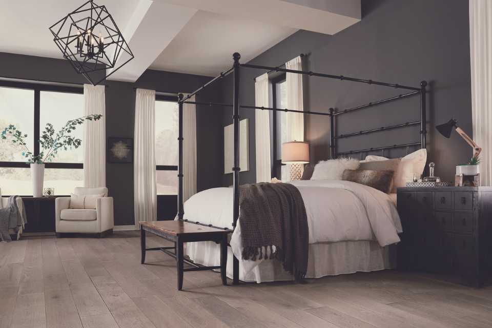 grey washed hardwood in cozy grey bedroom with greenery, fuzzy throw, and fun lighting